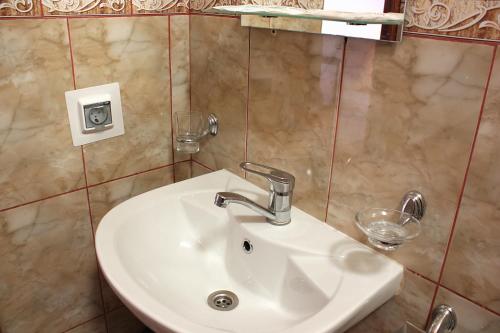 a bathroom with a sink and two glasses on the wall at Buhta Udachi Mini-hotel in Gelendzhik