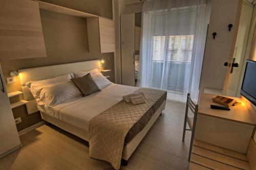 a bedroom with a bed and a desk and a television at San Marco in Marotta