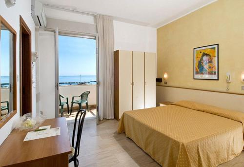 a hotel room with a bed and a table and a balcony at Hotel Arabesco in Rimini