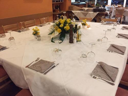 a long white table with glasses and flowers on it at Hotel Concordia in Porlezza