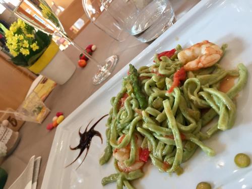 a plate of green pasta and shrimp on a table at Hotel Concordia in Porlezza