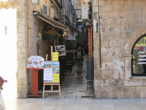 Una mujer caminando por un callejón en una ciudad en Apartments Giron, en Dubrovnik