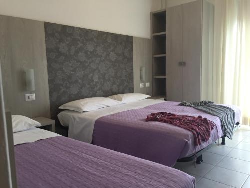 里米尼的住宿－雷登斯酒店，酒店客房,配有两张带紫色床单的床