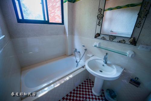 a bathroom with a sink and a tub and a toilet and a mirror at Rainbow SpringYU B&B in Nanzhuang