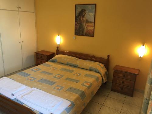 a bedroom with a bed with two night stands and two lamps at Argo Apartments in Néa Kíos