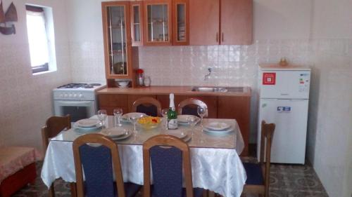 una cucina con tavolo, sedie e frigorifero bianco di Tor Holiday House a Kaštela (Castelli)