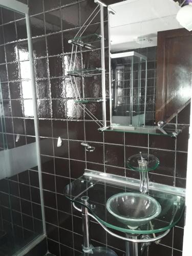Baño de azulejos negros con lavabo y espejo en Lindavista La Paz Apartamento, en La Paz