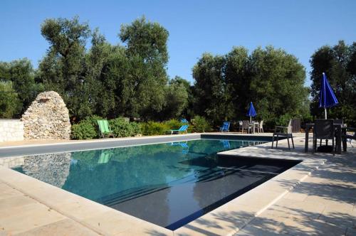einen Pool mit einem Tisch, Stühlen und Bäumen in der Unterkunft Tenuta Arcangelo in Ceglie Messapica