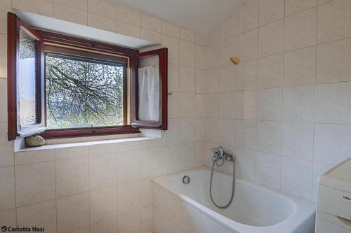 a bathroom with a bath tub and a window at La Calla in Monghidoro