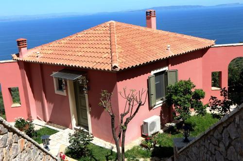 a pink house with the ocean in the background at Dio Guesthouses in Leonidion