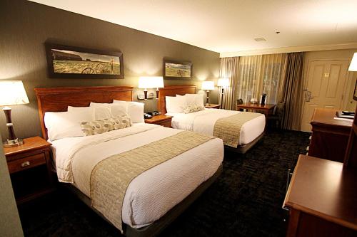 a hotel room with two beds and two lamps at C'mon Inn Grand Forks in Grand Forks