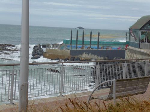 a bench sitting on the beach near the ocean at Rosemount B&B by the Sea St Clair in Dunedin