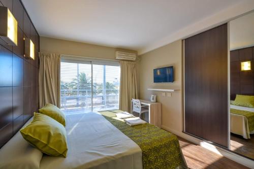 a bedroom with a large bed and a large window at Hotel Alpre in Villa Carlos Paz