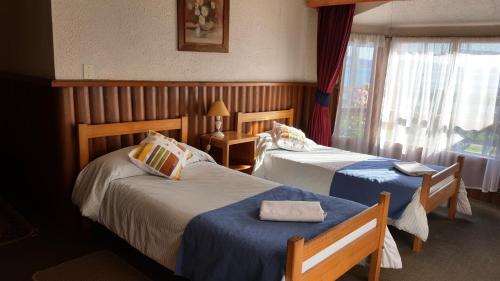 a hotel room with two beds and a window at Hostal Vista al Mar hct in Ancud