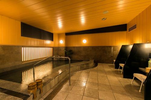 a swimming pool in a room with a table and chairs at Nishitetsu Inn Kurosaki in Kitakyushu