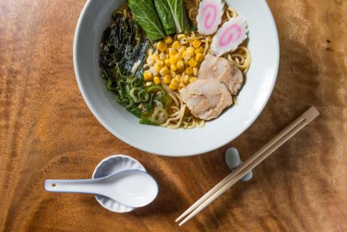 a bowl of noodles with meat and vegetables with chopsticks at Microtel by Wyndham South Forbes near Nuvali in Santa Rosa