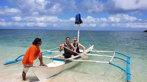 three people sitting on a boat on the beach at White Beach Front and Cottages in Buruanga