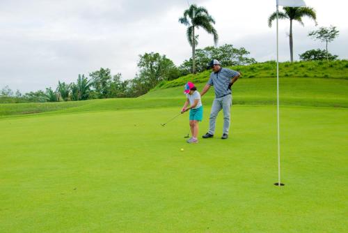 a man and a woman playing golf on a golf course at Microtel by Wyndham South Forbes near Nuvali in Santa Rosa