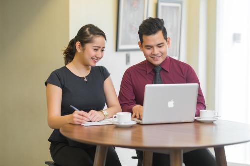 a man and a woman sitting at a table with a laptop at Microtel by Wyndham South Forbes near Nuvali in Santa Rosa