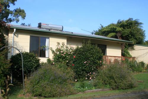 a house with a flowering bush in front of it at Strathmore Farm B&B in Mirboo North