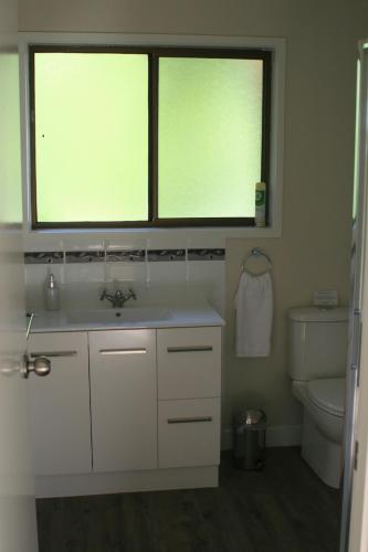 a bathroom with a sink and a toilet and two windows at Strathmore Farm B&B in Mirboo North