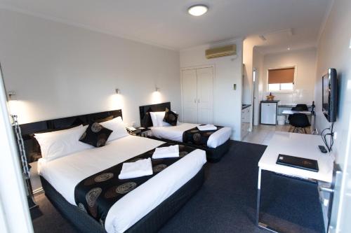a hotel room with two beds and a desk at Best Western Mill Park Motor Inn in Morang