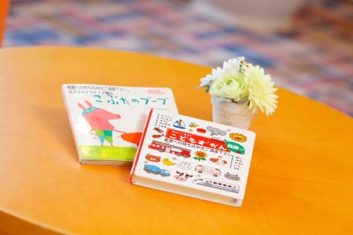 a table with two books and a vase of flowers at HOTEL MYSTAYS Maihama in Urayasu