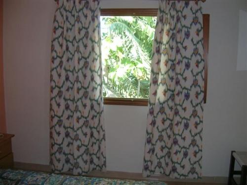 a bedroom with a window with curtains on it at Pensión Las Tres Golondrinas in Es Figueral Beach