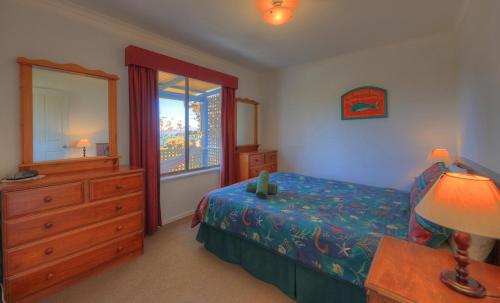 a bedroom with a bed and a dresser and a window at Sommers Bay Beach House in Murdunna