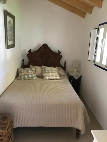Schlafzimmer mit einem großen Bett mit einem Kopfteil aus Holz in der Unterkunft Monte Antonio Domingos in Melides