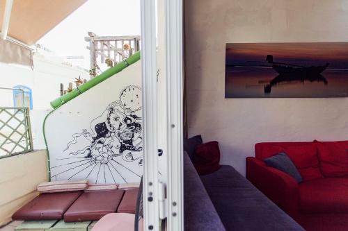 a living room with a red couch and a drawing on the wall at Granny's Inn Hostel in Sliema