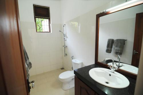 a bathroom with a sink and a toilet and a mirror at Park Lane Apartments in Negombo