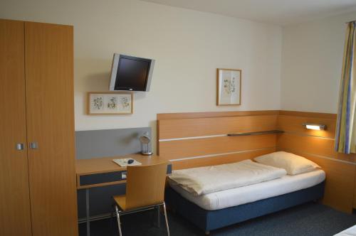 a bedroom with a bed and a desk with a television at Gästehaus der LK-Technik Mold in Mold