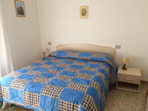 a bedroom with a blue and yellow bed and a nightstand at Hotel Nuova Doel in Sottomarina