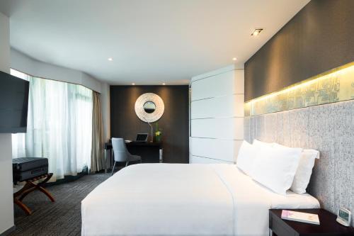 a hotel room with a white bed and a desk at Grand Mercure Shanghai Hongqiao in Shanghai
