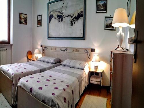 カルディエーロにあるB&B Happy Days Veronaのベッドルーム1室(ベッド2台、ランプ2つ、壁に絵画付)