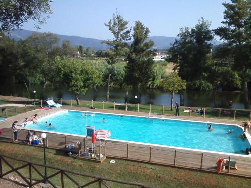 a large swimming pool with people in it next to a river at Casa de Alagoa in Arganil