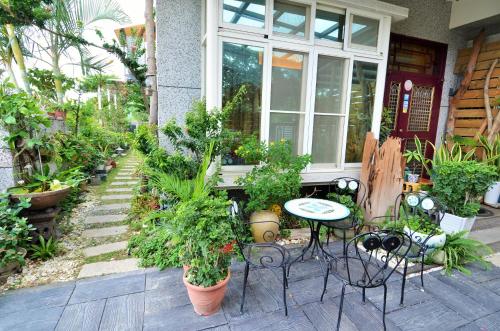 a porch with a table and chairs and plants at 旭緣咖啡民宿 in Taitung City
