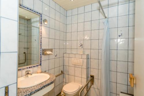 łazienka z umywalką, toaletą i lustrem w obiekcie Landpension Birker - Self Check-In w mieście Weißkirchen in Steiermark