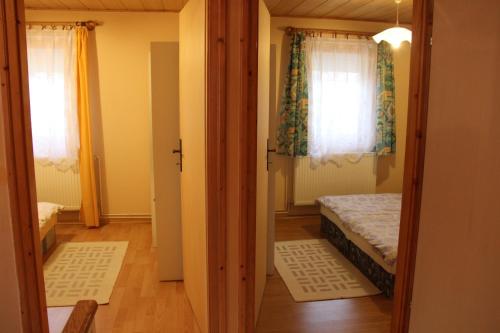 a small room with a bed and two windows at Lili nyaralóház in Gyenesdiás
