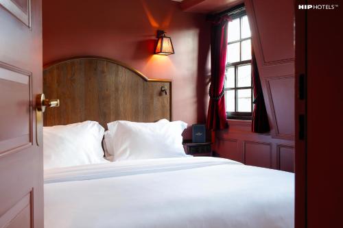 a bedroom with a large white bed with a wooden headboard at Mimi's Hotel Soho in London