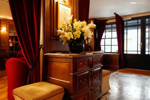 a vase of flowers on a dresser in a room at Mimi's Hotel Soho in London