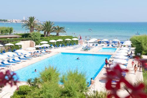 a large swimming pool with a beach and the ocean at Hotel Del Levante in Torre Canne