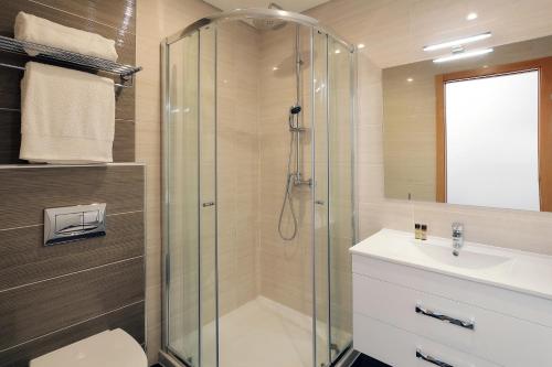 a bathroom with a glass shower and a sink at Sunfield Guest House - Only Adults in Albufeira