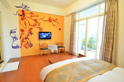 a bedroom with a bed and a table and a tv at 旭緣咖啡民宿 in Taitung City