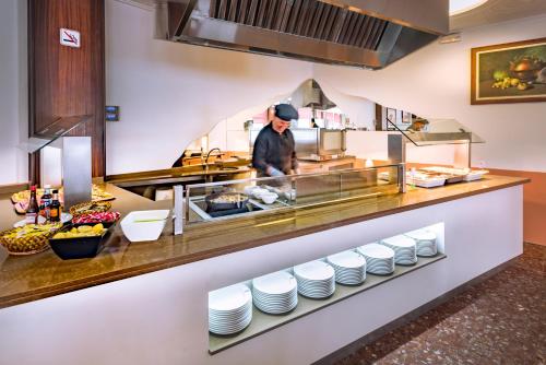 a chef preparing food in a restaurant kitchen at GHT Balmes, Hotel-Aparthotel&SPLASH in Calella