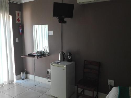 a room with a refrigerator and a television on the wall at Gemutlich Guesthouse in Upington