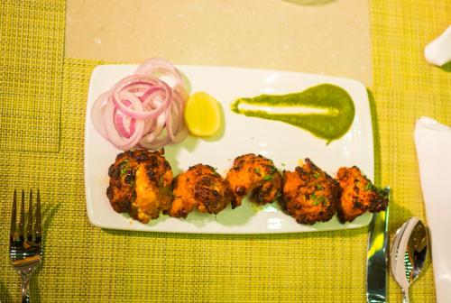 a plate of food with chicken and a pickle and onion at Niranta Transit Hotel Terminal 2 Arrivals/Landside in Mumbai