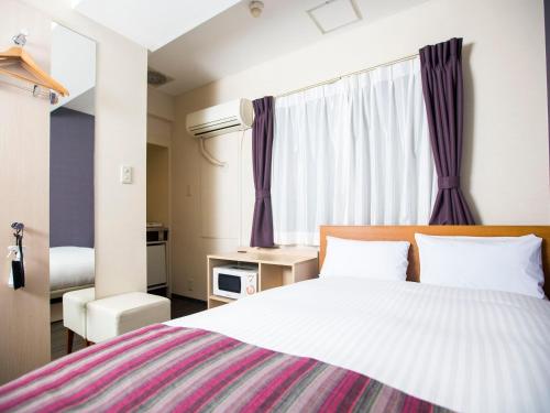 a bedroom with a large bed with purple curtains at FLEXSTAY INN Shinagawa in Tokyo