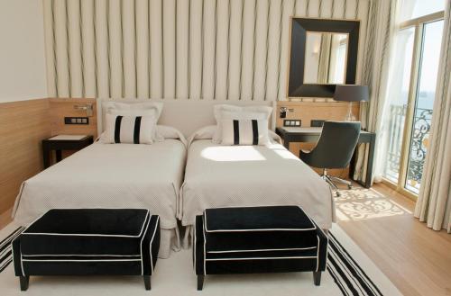 a bedroom with two beds and a desk and a mirror at Gran Hotel Sardinero in Santander